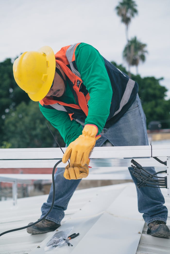 portfolio-02 A construction worker wearing PPE installs electrical equipment on a roof.