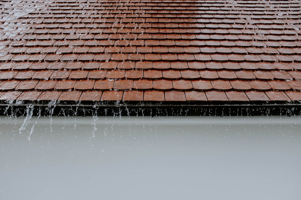 why-choose-us Brown roof tiles with rainwater cascading down, showcasing architectural texture and detail.